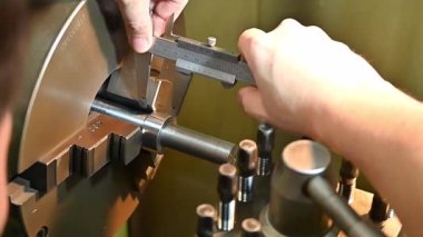 Yavaş çekim sahnesi metal şaft parçalarının boyutlarını ölçen makine operatörü vernier Caliper ile. Makine operatörü tarafından döndürülen makinede vernier caliper tarafından parçaların kalite kontrolü.