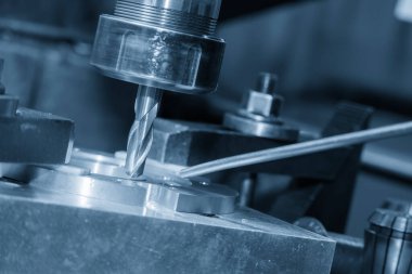 The hole drilling process the brass material parts on NC milling machine by drill tools in the light blue scene. The metal working concept on the milling machine.