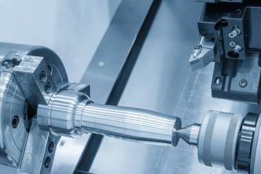 The operation CNC lathe machine finish cut the metal shaft parts in the light blue scene. The surface finishing process by turning machine. 