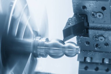 Olay yerini kapatın. CNC torna makinesi mavi tonlu sahnedeki metal şaft parçalarını tamamlıyor. Yüksek teknoloji metal işleme makinesini döndürerek çalışır..