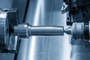 The operation CNC lathe machine finish cut the metal shaft parts in the light blue scene. The surface finishing process by turning machine. 