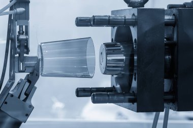 Açık mavi sahnedeki enjeksiyon küf makinesinin plastik parçaları üretimi. Sahneyi kapat. Mavi sahnede enjeksiyon makinesinin plastik cam parçaları.. 