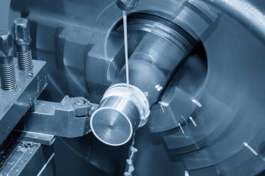 Torna makinesi, açık mavi sahnede metal şaft parçalarını sıvı soğutucu metoduyla kesiyor. Makineyi döndürerek metal işleme süreci.