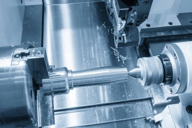 The operation CNC lathe machine finish cut the metal shaft parts in the light blue scene. The surface finishing process by turning machine. 