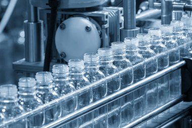 Açık mavi sahneyi doldurmak için konveyör bandındaki boş içme suyu şişeleri. İçme suyu üretim sürecinin yüksek teknolojisi.