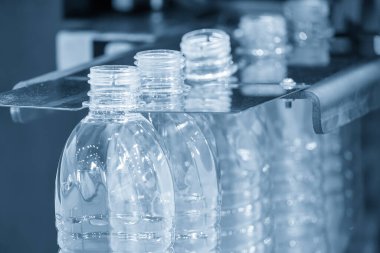 Açık mavi sahneyi doldurmak için konveyör bandındaki boş içme suyu şişeleri. İçme suyu üretim sürecinin yüksek teknolojisi.