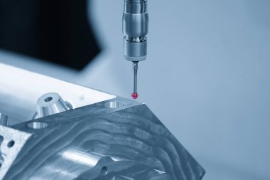 Açık mavi sahnede alüminyum silindir kafa parçalarını ölçen çok eksenli CMM makinesi. Çoklu eksen CMM makinesi ile otomotiv parçalarının kalite kontrolü.