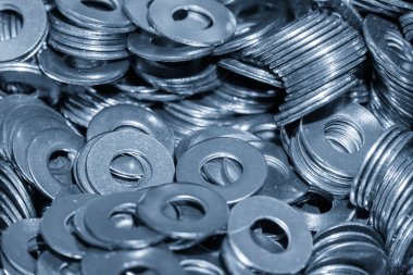 Seri üretim ve endüstriyel üretim sürecini temsil eden bir yığın çelik yıkama makinesi. Metal temizleyici bileşenleri açık mavi bir sahnede yığılmış, fabrika endüstrisi, mekanik parçalar, donanım parçaları ve metal işleme kavramları için uygun. İdeal