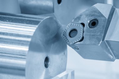 Metal şaftı indekslenebilir bir ekleme aracı kullanarak çalıştıran torna döndürme işleminin yakın plan görüntüsü. Süreç, soğutucu destekli koşullar altında kontrollü Milli döndürme ve besleme oranı, istikrarlı çip oluşumu ve tutarlı madde kaldırma göstermektedir