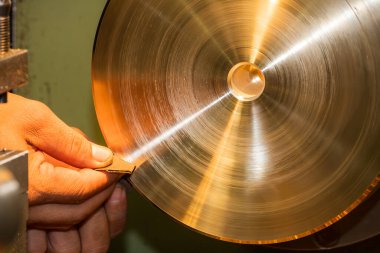 Torna makinesinin pirinç alaşımlı (demir alaşımlı olmayan) ikinci tamamlama işlemi. İşlemci, yüzey pürüzünü (R _ a) azaltmak için aşındırıcı zımpara kağıdı kullanır..