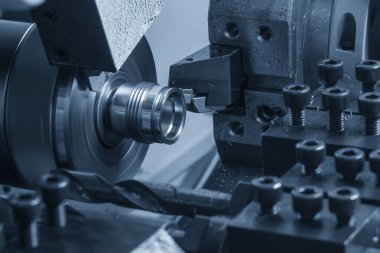 İsviçre tipi CNC torna kullanan küçük bir metal işindeki iplik kesme işlemi, yüksek uzunluklu, yüksek hassasiyetli parçalar üretmekle ünlü çoklu görev makinesi.