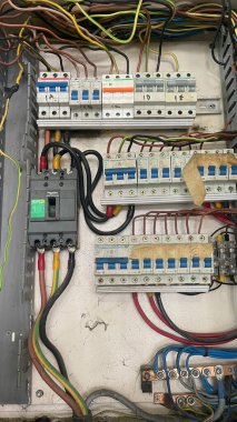 Devre kesiciler, kablolar ve bağlantılarla dolu bir elektrik paneli..