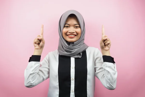 美しい若いアジアのイスラム教徒の女性は ピンクの背景に隔離されたカメラを見て 何かを提示する手で自信を持って 熱狂的かつ陽気な笑顔広告コンセプト — ストック写真
