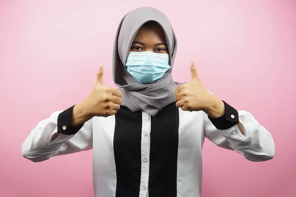 Muslim women wearing medical masks, anti corona virus movement, anti covid-19 movement, health movement using masks, with hands showing ok sign, good work, success, victory, isolated on pink background
