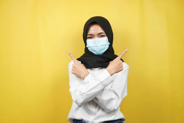 戴着医疗面具的穆斯林妇女 手指空旷的空间 手指着展示的东西 孤立在黄色背景下 — 图库照片