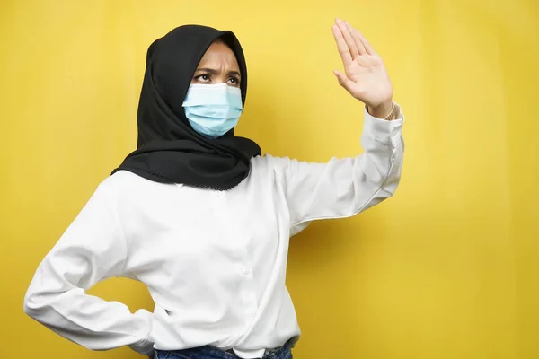 穆斯林妇女戴着医疗面罩 手拒绝某样东西 手停止某样东西 手不喜欢某样东西 被黄色背景隔离 — 图库照片
