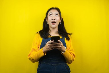 Güzel ve sevimli genç bir kadın şaşırdı, şok oldu, vay be yüz ifadesi, akıllı telefonu tutan, boş alana bakan, ürünü tanıtan, bir şey sunan, reklam veren, izole edilmiş