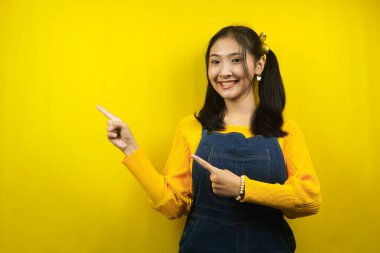 Güzel ve sevimli genç bir kadın, neşeli, kendinden emin, elleri boş yere bakıyor, bir şeyler sunuyor, ürünleri tanıtıyor, reklam yapıyor, izole ediyor.