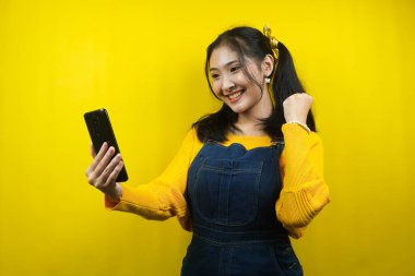 Güzel ve sevimli genç bir kadın, neşeli, kendinden emin, akıllı telefonu tutan, ürünü tanıtan, reklam veren, izole edilmiş