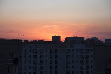 Siyah şehir silueti turuncu bir günbatımına karşı