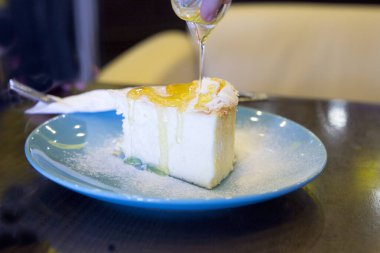 El peynirli kekin üzerine bal döker.