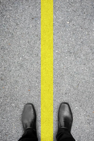 Scarpe nere in piedi sul pavimento e linea gialla — Foto Stock