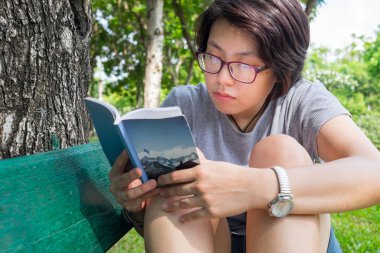 Parkta kitap okuyan kadın.