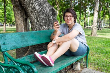 Asyalı kadın Smartphone parkta oynarken