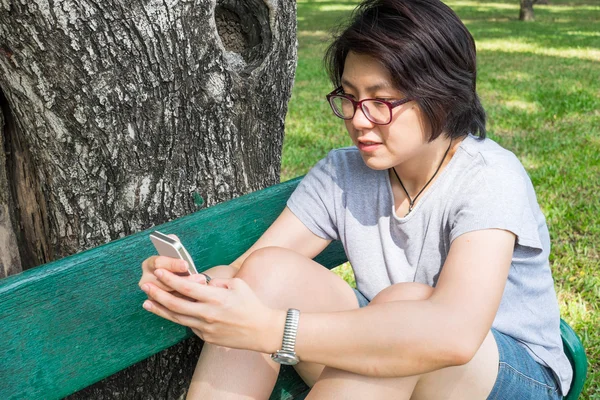 Asyalı kadın Smartphone parkta oynarken