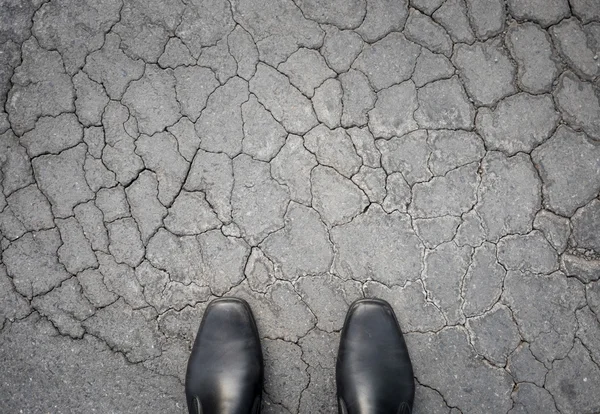 Zapatos negros de pie en el suelo dañado —  Fotos de Stock