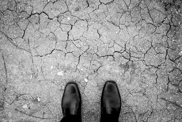 Black shoes standing on ground crack — Stock Photo, Image