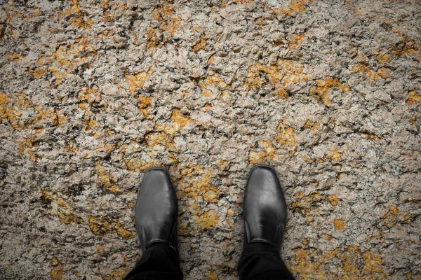 Zapatos negros de pie sobre la roca — Foto de Stock