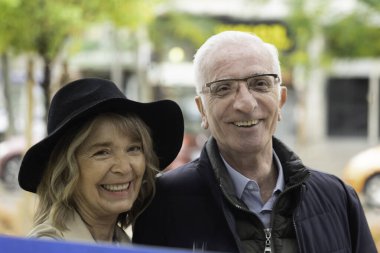 Dışarıda gülümseyen kıdemli çift mutluluk ve bağ gösteriyor.