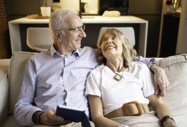 Mutlu son sınıf çifti kanepede oturuyor, gülümsüyor ve birbirlerine bakıyorlar.