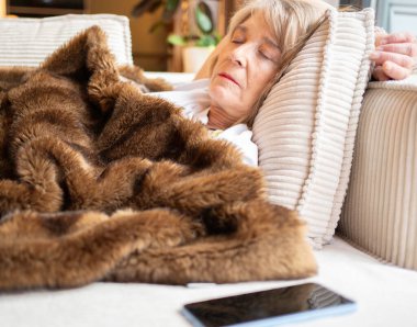 Sıcak, sahte bir kürk battaniyeyle kaplı, rahat bir kanepede uyuyan son sınıf öğrencisi kadın.