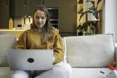Uzaktan kumandalı bir kadın oturma odasından kopyalanmış bir dizüstü bilgisayar kullanarak uzaklaşıyor.