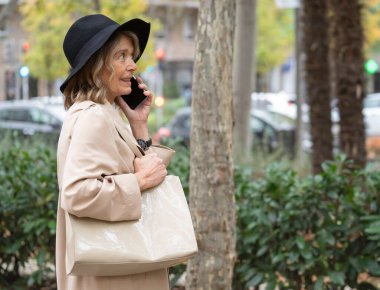 Şehrin caddesinde dururken akıllı telefondan konuşan zarif bir son sınıf öğrencisi.