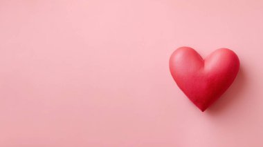 Kırmızı kalp, sevgililer günü için pastel pembe arka planda aşk ve romantizmi simgeliyor.