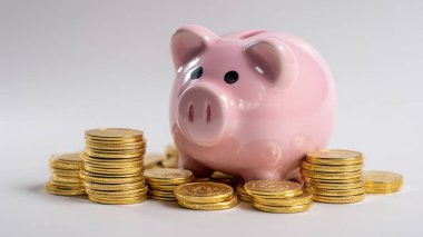 Altın para yığınlarının arasında duran pembe kumbara zenginliği ve yatırımı sembolize ediyor.