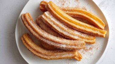 Kızartılmış altın sarısı churros, tatlı tarçın şekeri ile tozlanmış