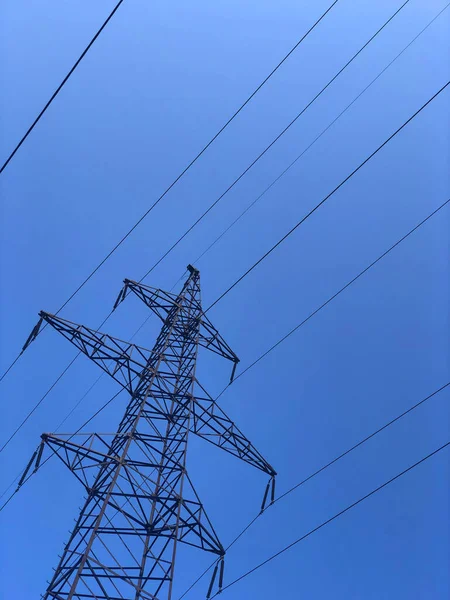 High voltage transmission line electric cables. High voltage tower against a clear blue sky background. Powerline technology pattern.