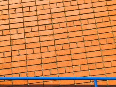 Turuncu tuğla duvar. Tasarım işleri için kopya alanı olan desenli arkaplan. Maddi desen. Kırmızımsı kahverengi tuğlalar mavi korkuluklu ön cephe. Tuğladan yapılmış endüstriyel duvar kağıdı. Kimse yok.