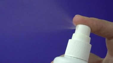 Mavi arka planda izole edilmiş beyaz plastik şişenin yakın görüntüsü. Şişeden fışkıran sprey..