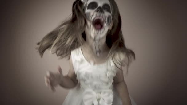 A little girl in a scary Halloween costume jumps, waves her head and scares everyone. — Stock Video