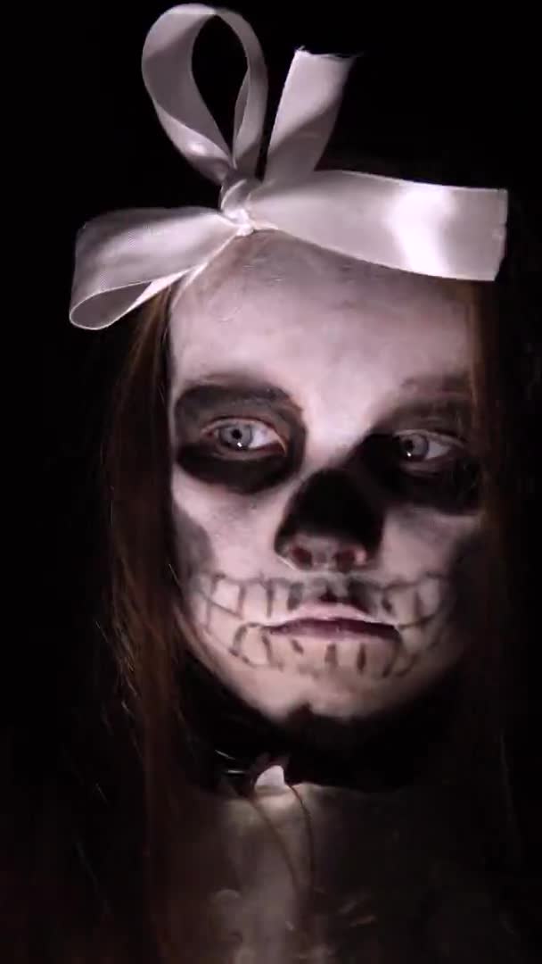 Mexican day of the dead.A little girl with terrible makeup on her face makes a grimace in the dark. — Stock Video
