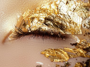  Kozmetik ve makyaj. Closeup makro moda sparcle Sima vurdu. Güzel genç kadının yüzündeki altın folyo ile portre portre. Yaratıcı makyaj. 