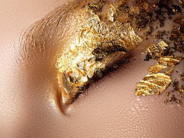  Kozmetik ve makyaj. Closeup makro moda sparcle Sima vurdu. Güzel genç kadının yüzündeki altın folyo ile portre portre. Yaratıcı makyaj. 