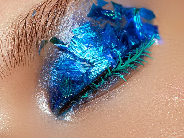 Cosméticos y maquillaje. Primer plano macro disparo de la moda sparcle visage. Retrato de cerca de una hermosa mujer joven con lámina azul en la cara. Maquillaje creativo . —  Fotos de Stock