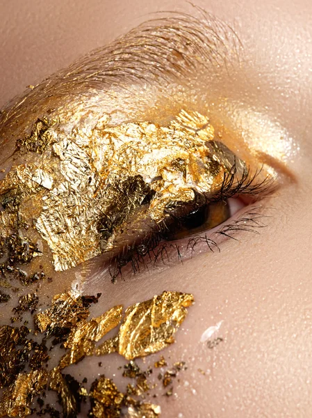 Cosmetics and make-up. Closeup macro shot of fashion sparcle visage. Closeup portrait of beautiful young woman with golden foil on face. Creative makeup. — Stock Photo, Image