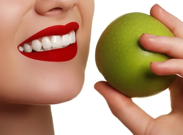 Primer plano de la cara de una mujer comiendo una manzana verde, aislada sobre fondo blanco. Hermosa cara de mujer adulta joven con piel limpia y fresca — Foto de Stock